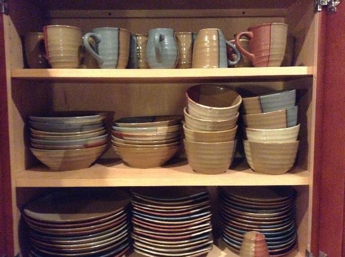 A pottery style of dishes with many place settings