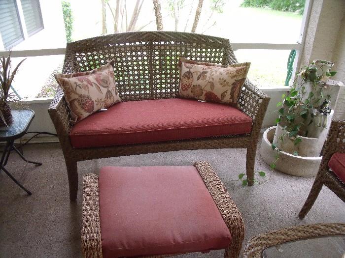 Plastic (outdoor) wicker settee with pad.  Outdoor wicker ottoman in foreground