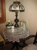 Another round side table with glass top and currier and Ives Lamp
