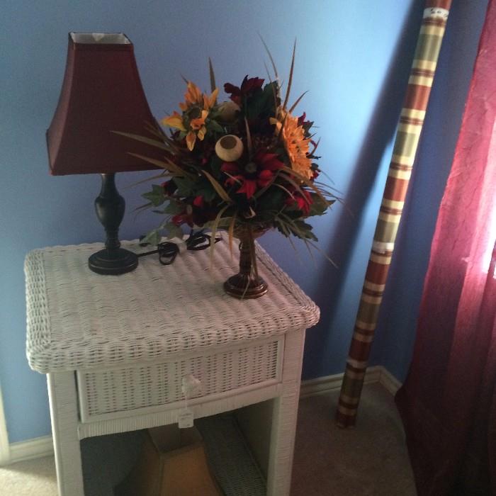 One of several white wicker side tables and floral arrangements