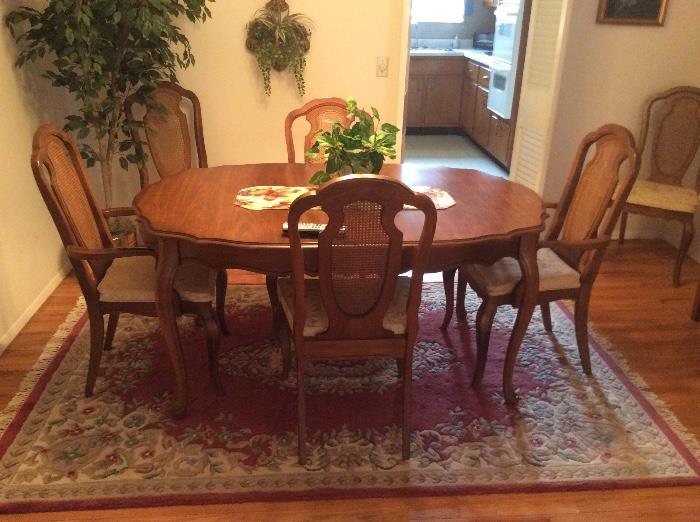 Bassett dining table with six cane backed chairs. Two arm chairs and four side chairs. Table has an 18 inch leaf.