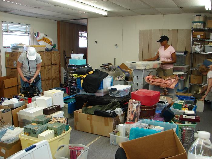 Joyce and Janet sorting boxes in the gift house - scarves, totes, shirts, holiday, collectibles.