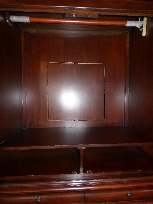 Interior of armoire showing clothes hainging rod