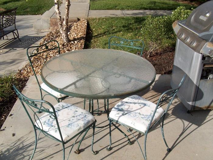 Green wrought iron and glass patio set with solid base cushioned seats $150.00 and Gas grill