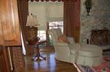 Marge Carson panel back chair and ottoman, round basketweave pedestal table with antiqued metal lamp, heavy iron fireplace screen